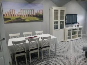 a dining room with a white table and chairs and a tv at Casa Rural La Plata in Aljucén