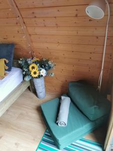 a small room with a bed and a table with flowers at The Forest Pod - Wood Fired Hot Tub and Fire Pit in Hambleton
