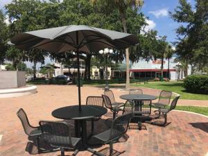 Historic Sebring Downtown Home في سيبرينغ: طاولة وكراسي مع مظلة في الحديقة