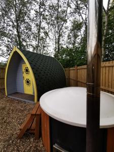 a backyard with a dog house and a table at Cosy Forest Pod with Wood Fired Hot Tub & Fire Pit in Hambleton