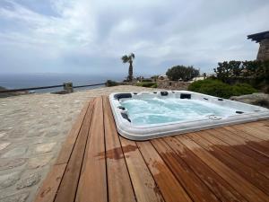bañera de hidromasaje en una terraza de madera con el océano en el fondo en Villa Elan Fanari, en Fanari