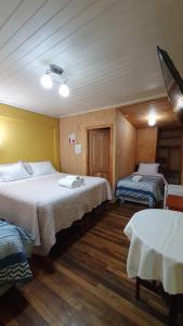 Habitación con 2 camas y mesa. en Hostal Las Heras, en Temuco
