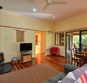 een woonkamer met een bank en een flatscreen-tv bij Williams Lodge in Yungaburra