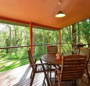 een afgeschermde veranda met een houten tafel en stoelen bij Williams Lodge in Yungaburra