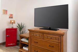 a flat screen tv on a wooden dresser with a television on it at The Sojourn Los Angeles - Sherman Oaks in Sherman Oaks