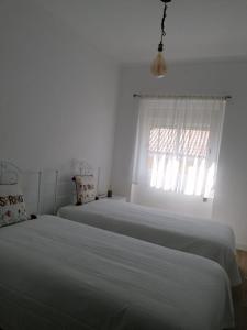 2 camas en una habitación blanca con ventana en Alojamento Justo - vila de Montargil, en Montargil