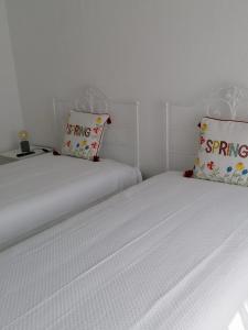 Habitación con 2 camas individuales y paredes blancas. en Alojamento Justo - vila de Montargil, en Montargil