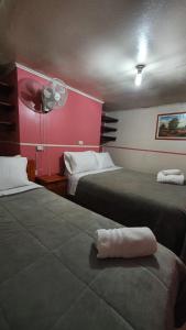 a hotel room with two beds and a fan at Hostal Las Heras in Temuco