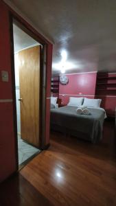 a bedroom with a bed with a red wall at Hostal Las Heras in Temuco