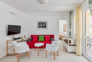 Apartment Pavle في كوتور: غرفة معيشة مع أريكة حمراء وكراسي بيضاء