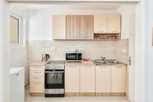 Apartment Pavle في كوتور: مطبخ بدولاب بيضاء وموقد ومغسلة
