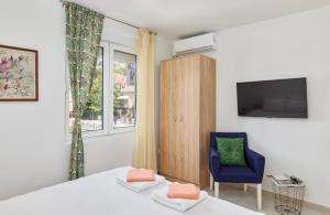 Apartment Pavle في كوتور: غرفة نوم بسرير وكرسي ازرق وتلفزيون