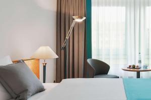 a hotel room with a bed and a lamp at Dorint Hotel Dresden in Dresden