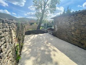 una pared de piedra con un árbol al lado de una acera en La Cascade verte /Appartement /jardin /parking en Braux