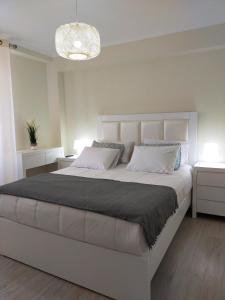 um quarto com uma grande cama branca com duas mesas de cabeceira em Brisa Do Mar - Consolação em Peniche