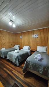 2 camas en una habitación con paredes de madera en Hostal Las Heras, en Temuco