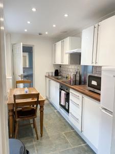 kuchnia z białymi szafkami i drewnianym stołem w obiekcie 147 knapp road house w Londynie
