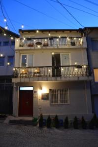 a white house with a balcony with lights on it at Moonlıght Hostel in Prishtinë