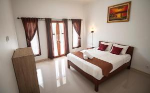 a bedroom with a large bed with red pillows at Santhi Guna Bungalow in Nusa Penida