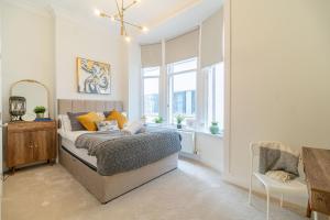 a bedroom with a bed and a desk and windows at Large Blythswood Residence in Glasgow