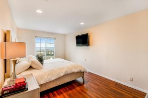 a bedroom with a bed and a tv on the wall at I Only Have Eyes for You in Newport Beach