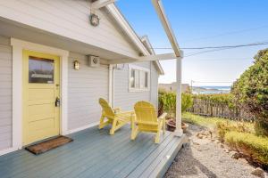 a house with a yellow door and two chairs on a porch at Seaside Cottage in Bodega Bay