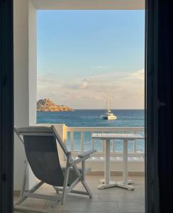 a table with a chair near a window with a view of the ocean at Acrogiali Beach Hotel Mykonos in Platis Gialos
