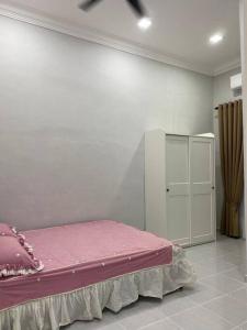 a bedroom with a pink bed and a white cabinet at afza Homestay Paka B in Paka