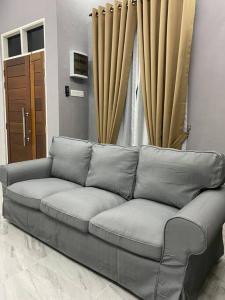 a gray couch in a room with a window at afza Homestay Paka B in Paka