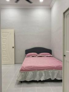 um quarto com uma cama com lençóis e almofadas cor-de-rosa em afza Homestay Paka B em Paka