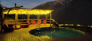 een terras met een hot tub, stoelen en verlichting bij Cabañas "Terrazas de Orión" con Vista Panorámica en Pisco Elqui in Pisco Elqui