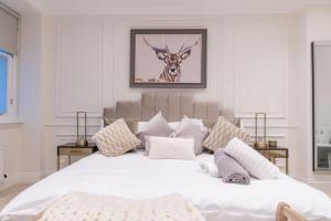 a bedroom with a large white bed with a deer picture on the wall at Large Blythswood Residence in Glasgow +4 photos