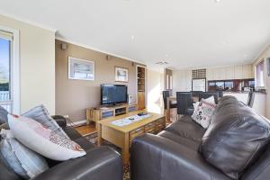 a living room with two leather couches and a television at The Dunes 1 in Apollo Bay