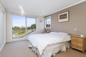 a bedroom with a bed and a large window at The Dunes 1 in Apollo Bay