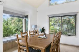 a dining room with a wooden table and chairs and windows at Lorne Central in Lorne
