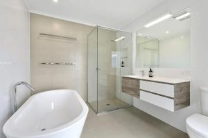 a white bathroom with a tub and a sink at Lorne Central in Lorne +7 photos