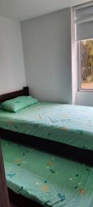 2 camas individuales en un dormitorio con ventana en comodo Apartamento alojamiento Pereira Gamma, en Pereira