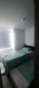 Una pequeña habitación con dos camas y una luz en la pared. en comodo Apartamento alojamiento Pereira Gamma, en Pereira