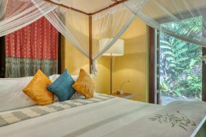 a bedroom with a bed with colorful pillows at Living Heritage Koslanda in Koslanda