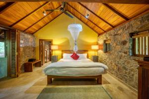 a bedroom with a bed and a stone wall at Living Heritage Koslanda in Koslanda