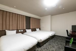 a hotel room with two beds and a flat screen tv at Hotel Silk Tree Nagoya in Nagoya