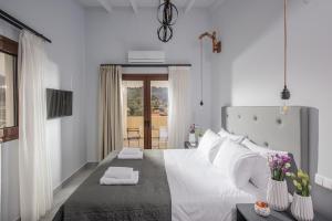 1 dormitorio blanco con 1 cama grande con almohadas blancas en Iris Villa 2 - Archanes Crete, en Káto Arkhánai