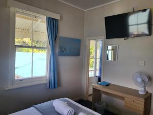 a bedroom with a bed and a television on the wall at Mangonui Hotel in Mangonui