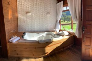 a jacuzzi tub in a room with a window at Chão de Estrelas Cabanas in Urubici