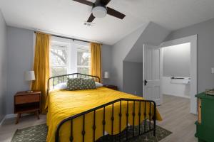 a bedroom with a bed with a yellow blanket at SAND HILL COTTAGE 3 Bedroom Home near PURDUE! River & Park View in West Lafayette
