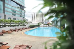 a large swimming pool in a building with benches at Golden Tulip Sovereign Hotel Bangkok in Bangkok
