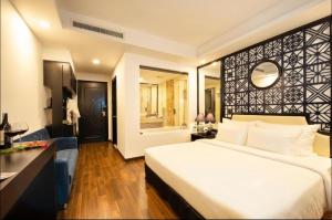 a bedroom with a large white bed and a bathroom at Adora Art Hotel in Ho Chi Minh City