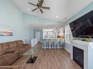 a living room with a couch and a kitchen at Pelican Watch - Steps away from a beautiful beach in a prime location home in Carolina Beach