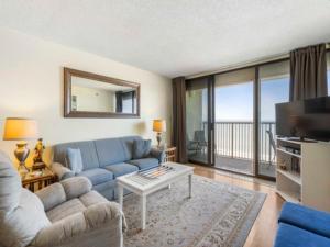 a living room with a blue couch and a television at Casa Pelicano - OCEANFRONT LUXURY! Enjoy epic ocean views from this 7th floor dream condo condo in Carolina Beach