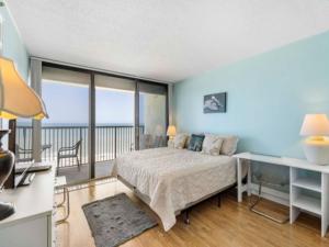 a bedroom with a bed and a balcony at Casa Pelicano - OCEANFRONT LUXURY! Enjoy epic ocean views from this 7th floor dream condo condo in Carolina Beach +18 photos